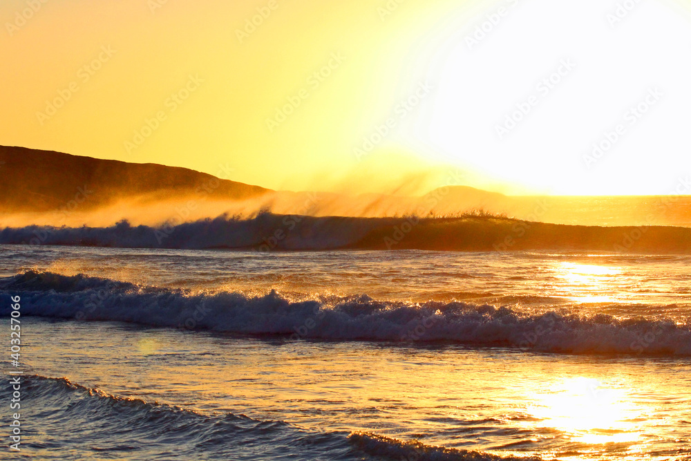 Brechende Wellen und Brandung während der goldenen Stunde vor Sonnenuntergang an der Küste von Kapstadt in Südafrika