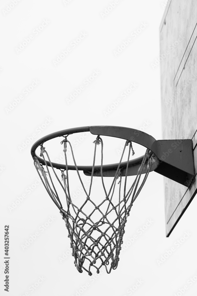 Basketball hoop, basket with white net and white blown up sky in background Basketball hoop, basket with white net and white blown up sky in background