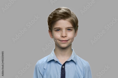 Close up cute smiling boy on gray background. Portrait of handsome stylish child looking at camera.