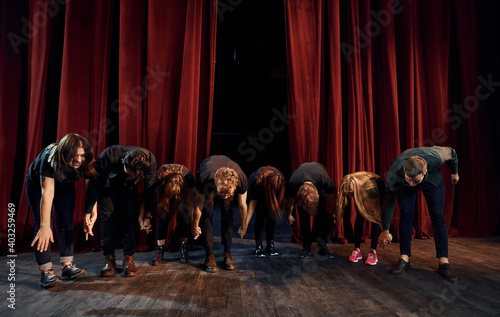 People bowing to audience. Group of actors in dark colored clothes on rehearsal in the theater