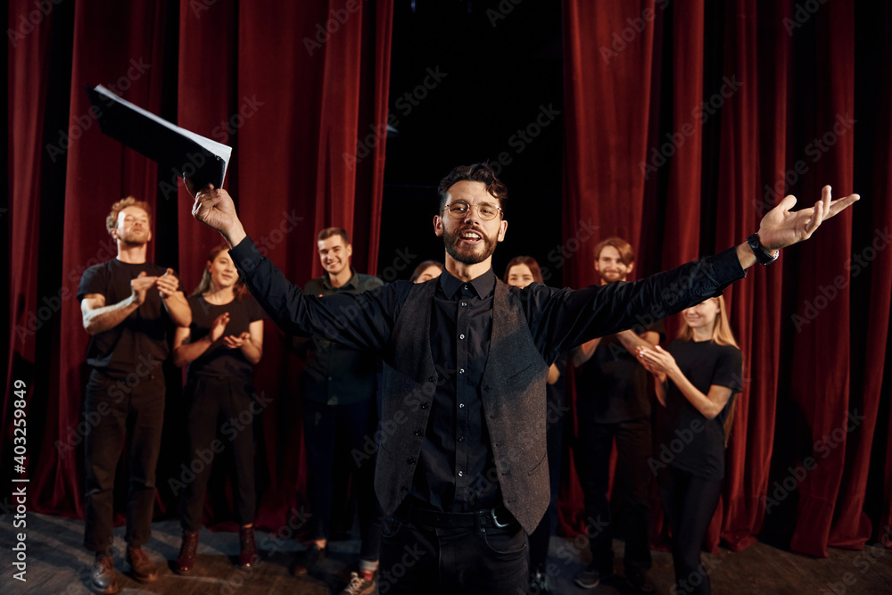 Fototapeta premium Man is practicing his role. Group of actors in dark colored clothes on rehearsal in the theater