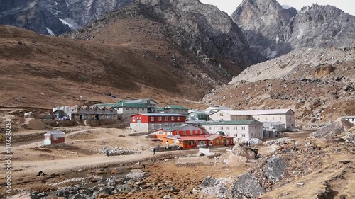 View of small Sherpa village Lobuche, mainly lodges in traditional stone houses, in Khumbu, Nepal at high altitude with people passing by and rugged mountains on Everest Base Camp Trek. photo