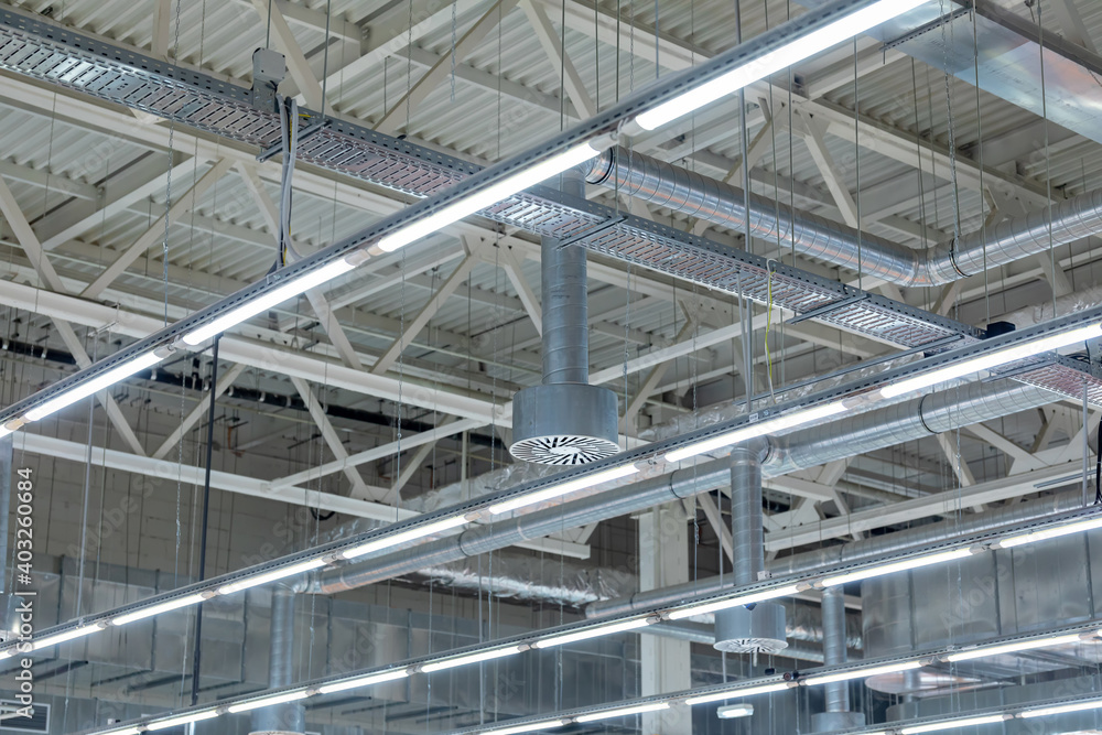 Lamps with diode lighting and ventilation under the ceiling of a modern warehouse or shopping center. Ceiling air conditioning of the stadium or exhibition hall roof.