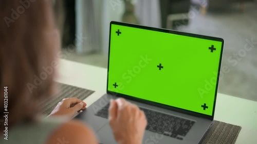 Close up of mock up green screen of modern aluminium laptop on table