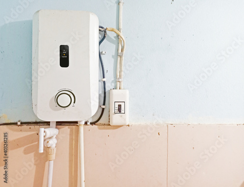White instant water heater installed with circuit breaker on the wall of bathroom with free copy space. Safety first concept.