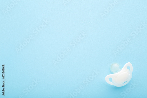 Vászonkép White silicone baby soother on light blue table background