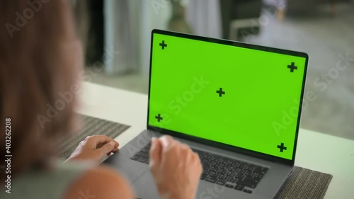 Girl working on laptop with Mock up green screen on the table in modern living room
