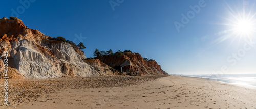 Canvas Print panorama view of a wide empty golden sand beach with colorful sand cliffs on a s