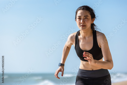 Asian healthy sport athlete girl running or jogging on beach in morning