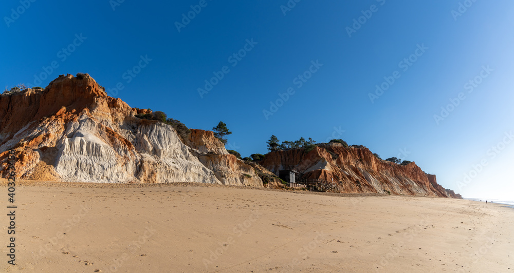 panorama view of a wide empty golden sand beach with colorful sand cliffs on a sunny day panorama view of a wide empty golden sand beach with colorful sand cliffs on a sunny day