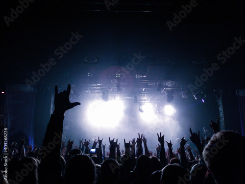 silhouettes of people at the concert in the bright light of the stage lights. hands of people in the concert hall. a lot of people in the audience are pointing with their fingers.