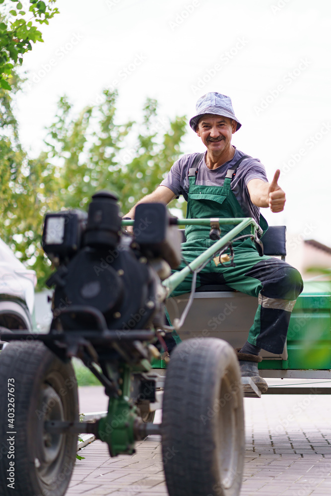 Satisfied farmer portrait sitting behind the wheel of a two-wheeled tractor.