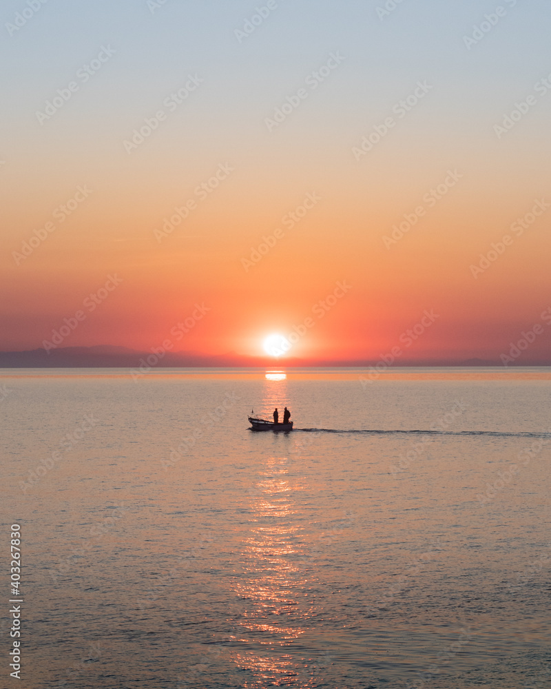 Silhouette of two fishermen on a boat at sunrise