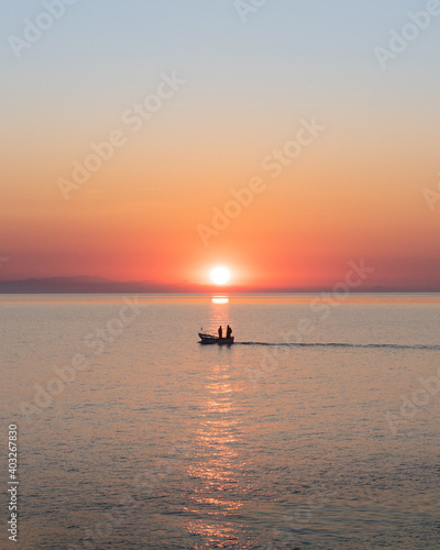 Silhouette of two fishermen on a boat at sunrise