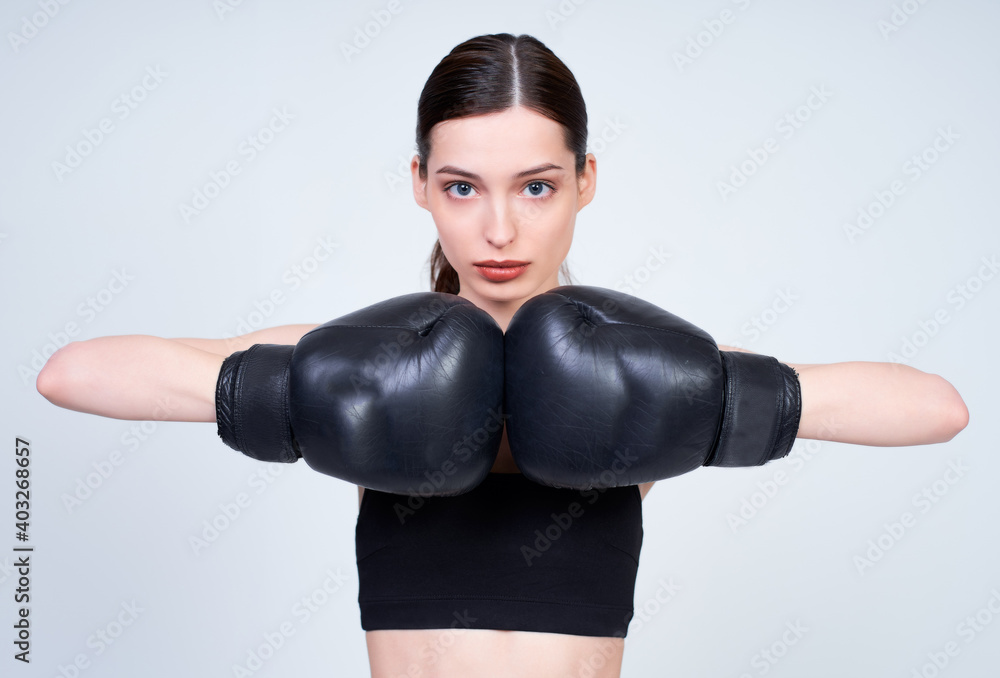 Serious athletic caucasian girl in black boxing gloves.
