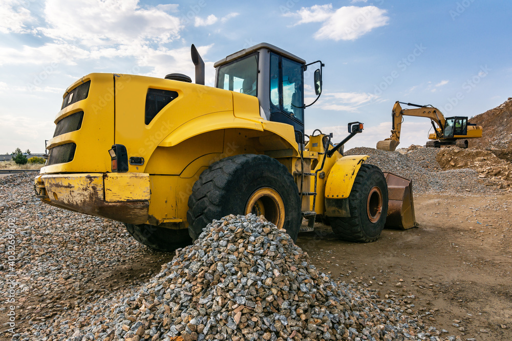 Fototapeta premium Heavy machinery, excavators at a construction site with stone and rock