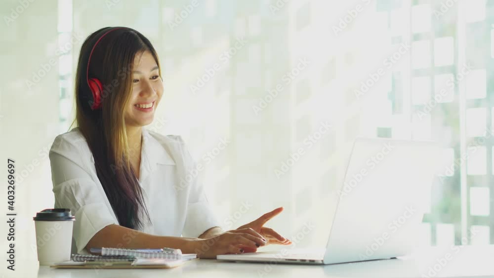A young woman who wears headphones and works at home talking on a laptop A young woman who wears headphones and works at home talking on a laptop