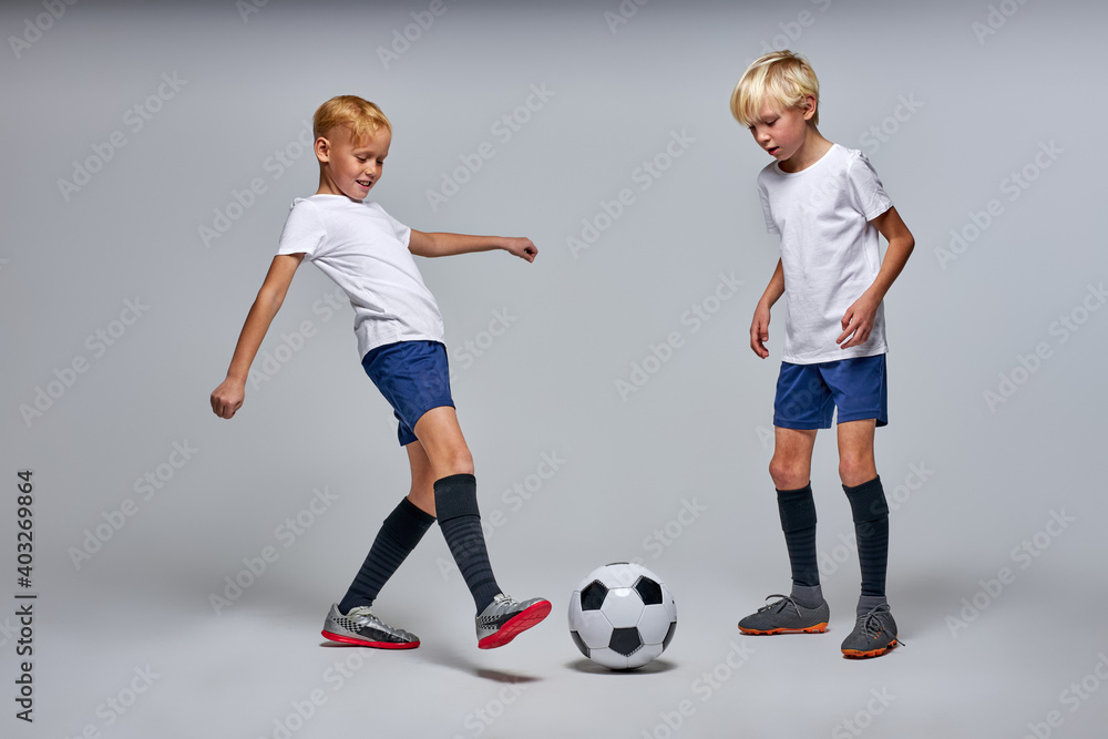 kids play soccer isolated in studio, caucasian boys in sportive wear play football. sports, children's games and active entertainment