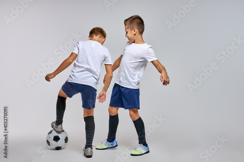 children soccer team on training, two boys practicing game with a soccer ball in studio. training football session for children on soccer camp. young boy improving dribbling skills
