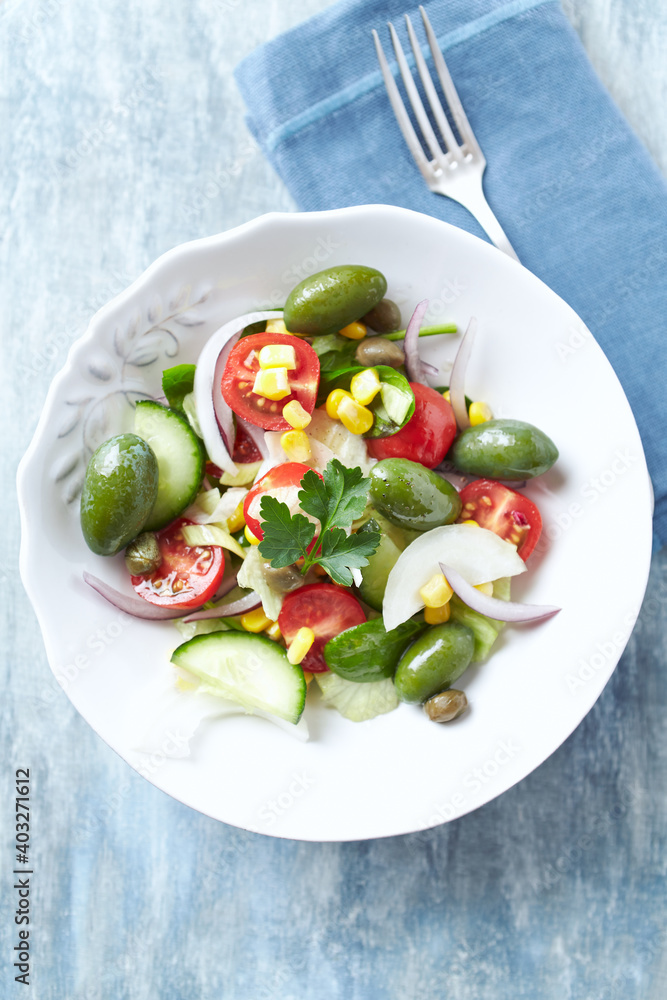 Healthy Salad with Green Olives, Baby Spinach, Cucumber, Cherry Tomatoes and Capers. Bright wooden background. Top view. Close up. Healthy Salad with Green Olives, Baby Spinach, Cucumber, Cherry Tomatoes and Capers. Bright wooden background. Top view. Close up.