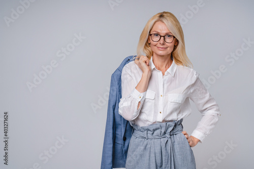 Confident senior business woman in formal attire isolated over grey background