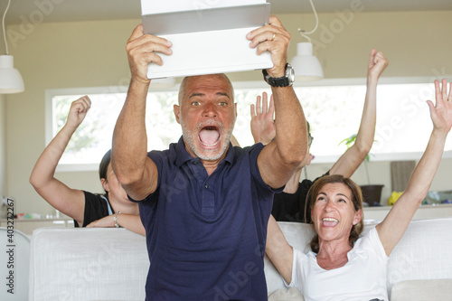 Componenti di una famiglia esultano giocando a un gioco elettronico nel salotto di casa photo