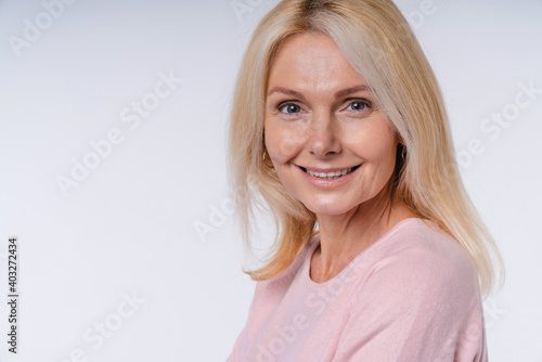 Cropped portrait of smiling mature european woman in casual clothes isolated over grey background