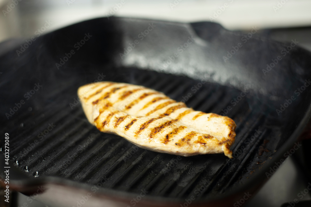 Chicken fillet cooking on the grill pan at home.
