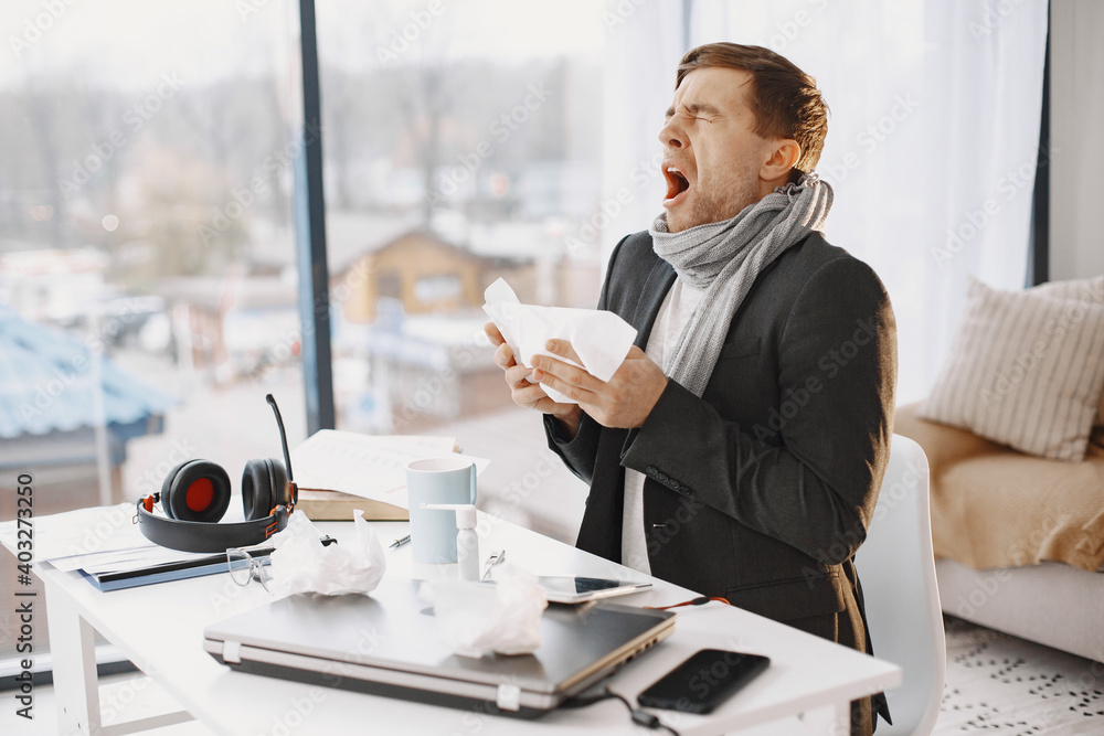 Man with a laptop is suffering with cough and feeling bad. Businessman at home. Man with a laptop is suffering with cough and feeling bad. Businessman at home.