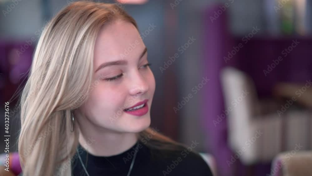 Beautiful young woman flirts and smiles while sitting in a restaurant. Beautiful young woman flirts and smiles while sitting in a restaurant.