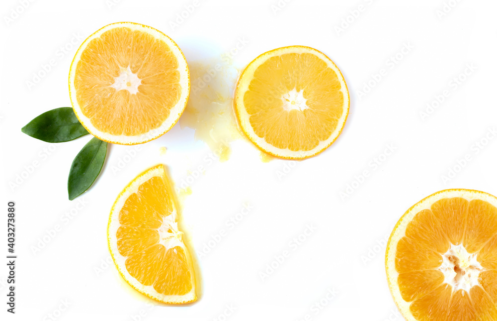Orange slices with green leaves and spilled orange juice on a white background.