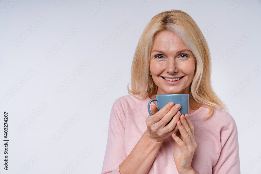 Happy smiling caucasian senior woman with a cup isolated over grey background Happy smiling caucasian senior woman with a cup isolated over grey background