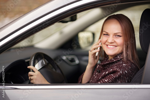 Woman In Car Talking On Mobile Phone Whilst Driving. Attractive woman uses smart phone while driving.