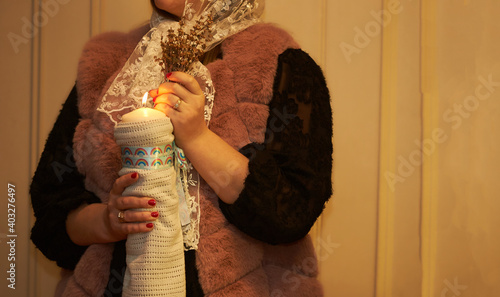 Fényképezés Female hands holding bouquet of flowers with candle in the church at baptism