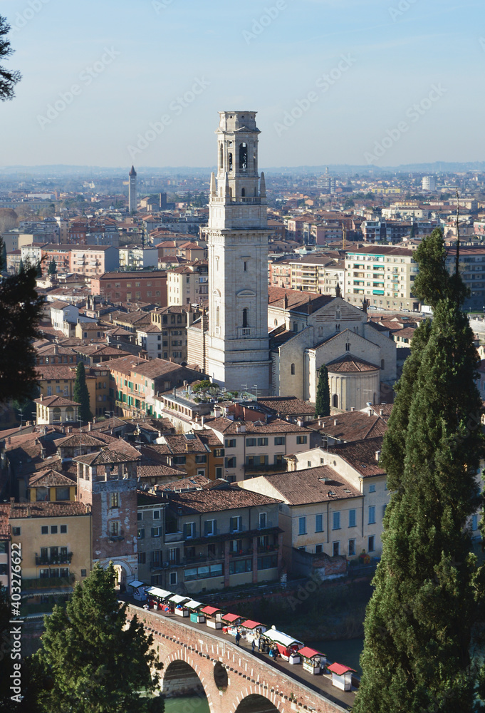 Fototapeta premium Top view of the old church with a bell tower and a bridge with shopping stalls over the Adige river in Verona.