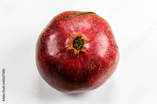Red ripe pomegranate fruit against a white background. Anthers on ripe fruit up close. Rind outer skin of pomegranate. Macro of pomegranate fruit. Picture from top to bottom.