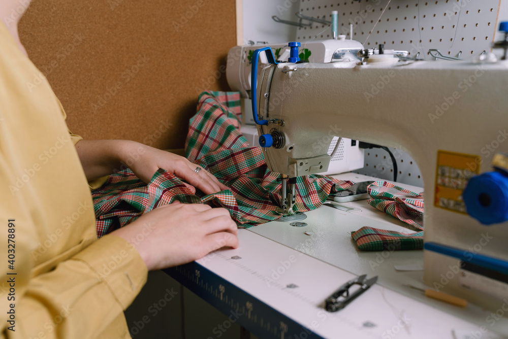 Closeup of a woman working with sewing machine in her workshop