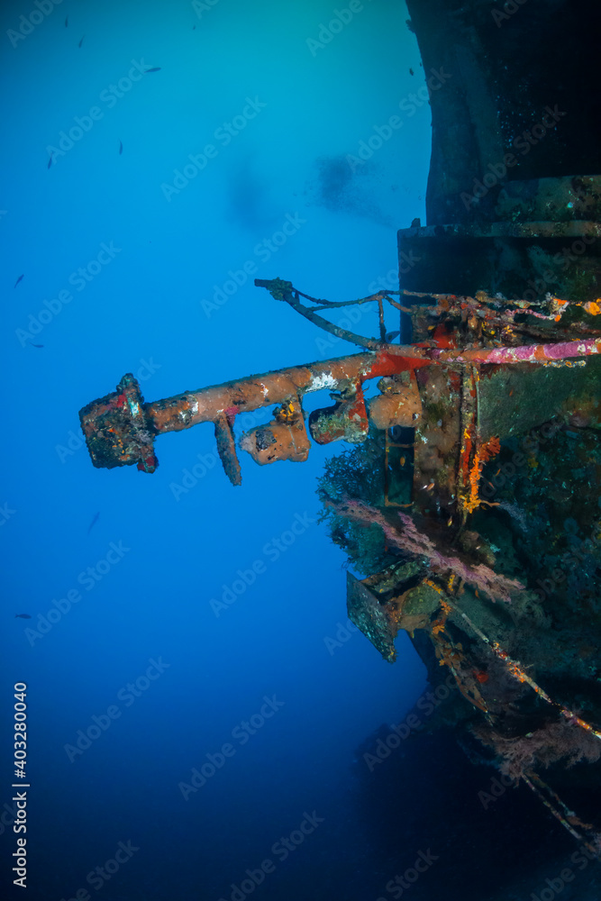A large, upturned shipwreck on the sea floor near a tropical coral reef