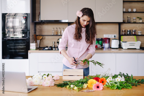 Florist at work  pretty young brunette woman making fashion modern composition of different flowers at home