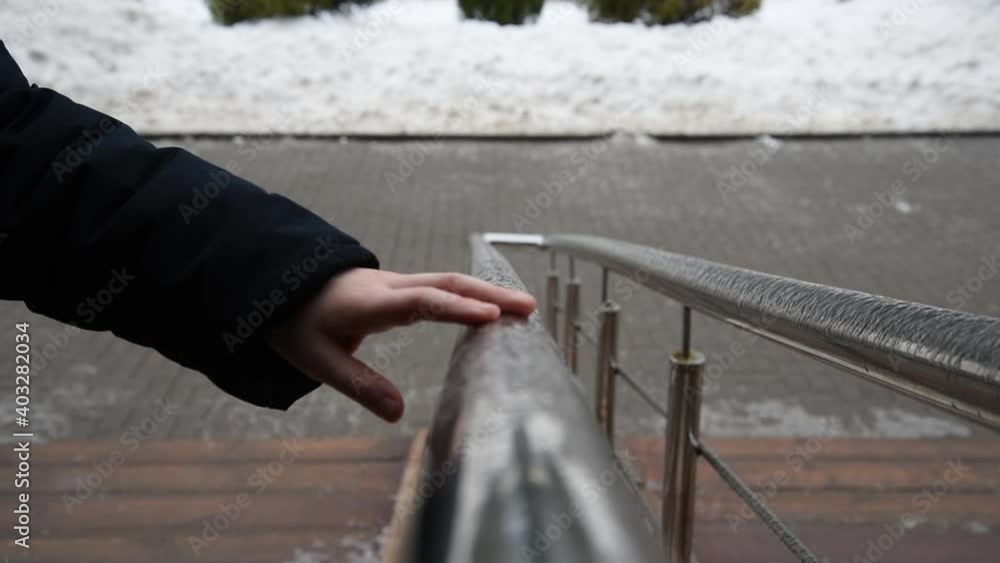 A hand touches the frozen handrails. Freezing rain. Cold season and frost A hand touches the frozen handrails. Freezing rain. Cold season and frost