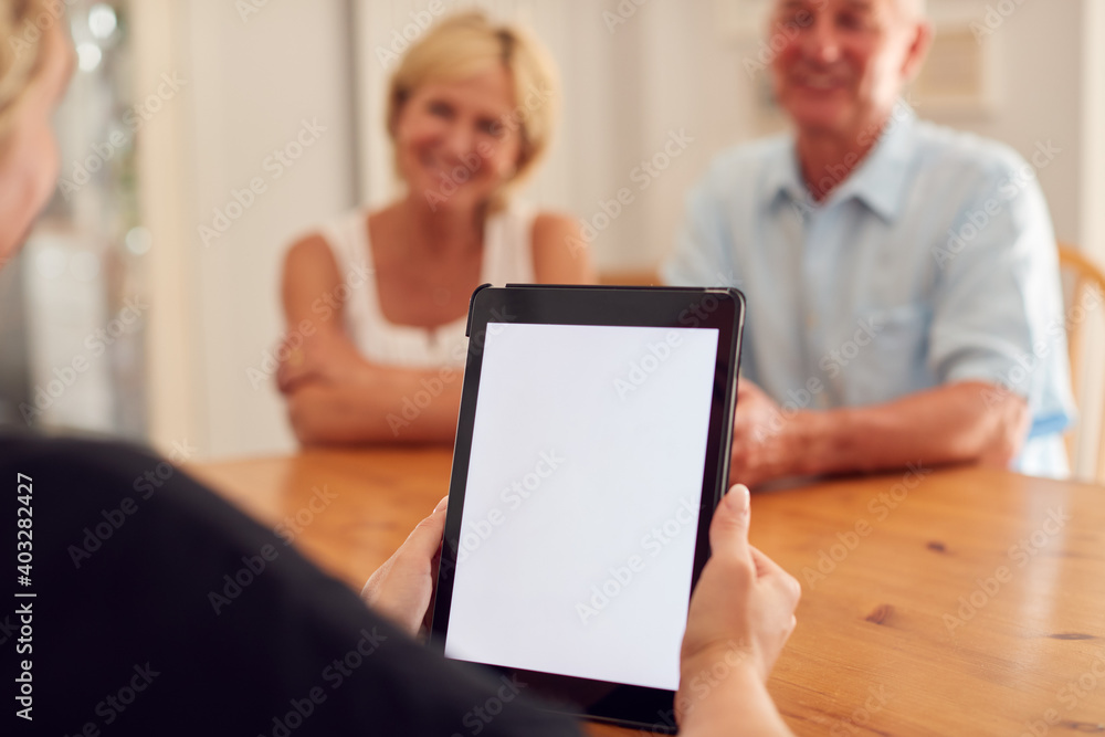 Close Up On Blank Screen Of Digital Tablet As Retired Couple Meeting With Financial Advisor At Home Close Up On Blank Screen Of Digital Tablet As Retired Couple Meeting With Financial Advisor At Home