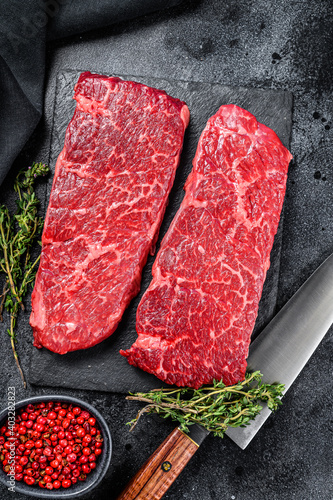 Raw Denver steak. Marble beef meat. Black background. Top view.