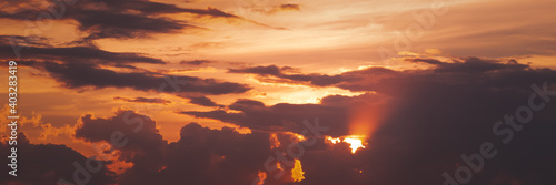 Beautiful sunset sky above clouds with dramatic sunshine light. Panorama banner format.