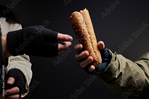 Fotografija close-up photo of homeless people's hands sharing food, one bum give bread to ot