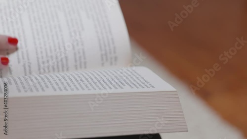 Une femme avec du vernis à ongle rouge qui lis un livre