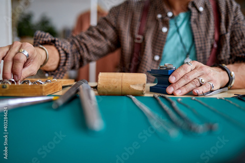 goldsmith working on a handmade jewelry in a workshop, skilled man use tools for repair. concept of jewelry, luxury, goldsmith, gold, silver, precious metals. focus on hands