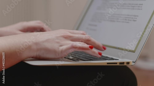 Une femme avec du vernis à ongle rouge qui tape sur un clavier d'ordinateur