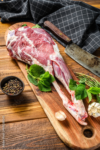Goat leg with pepper and garlic. Raw Farm meat. Wooden background. Top view