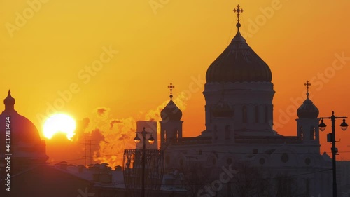 Telephoto shot of sun disk setting behind the Cathedral of Christ the Saviour
