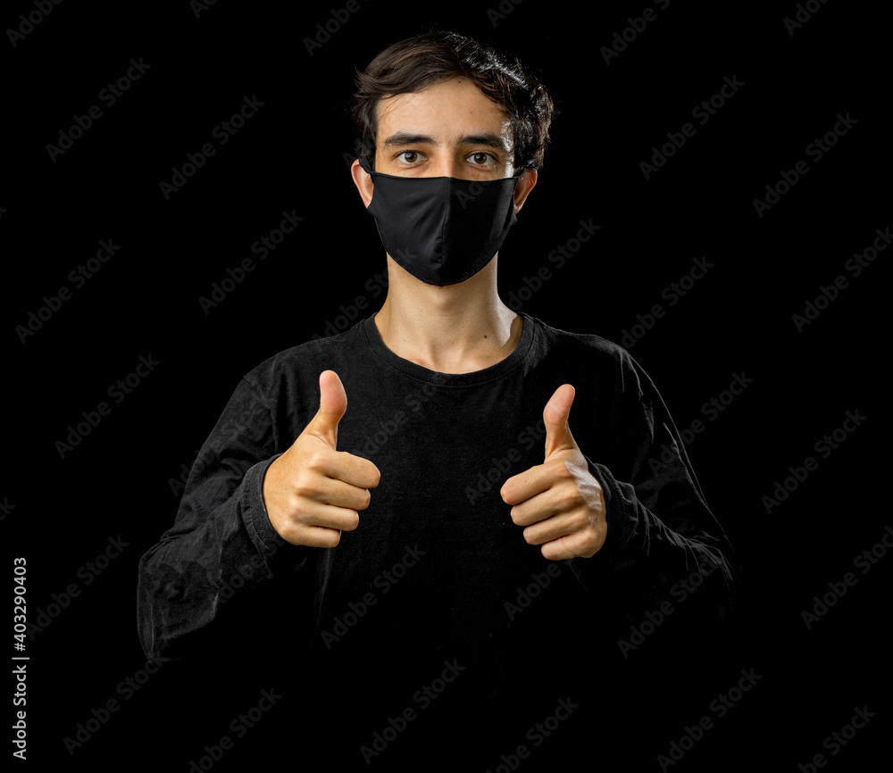Young man wearing black face mask. Pandemic coronavirus covid-19 quarantine period concept. Black background studio Young man wearing black face mask. Pandemic coronavirus covid-19 quarantine period concept. Black background studio